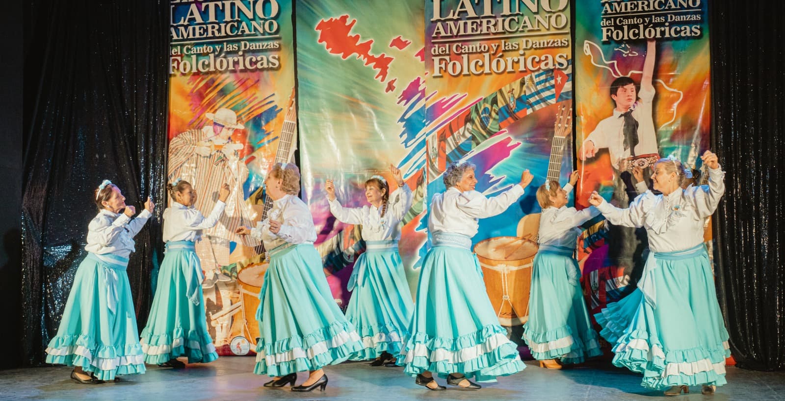 Grupo de mujeres con faldas celestes bailando folclore en el escenario del Encuentro